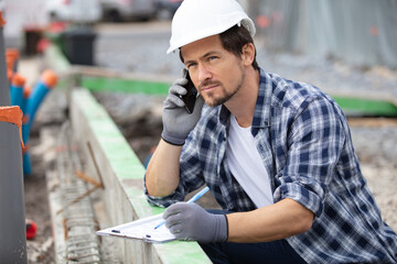 young builder talking a mobile phone at construction site
