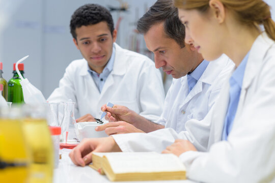 teacher and students scientists checking liquid in lab