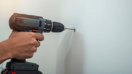 A person using a power drill to insert a screw into a wall, showcasing a home improvement or DIY project in action.