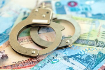 Bahraini dinar currency money bills and handcuffs close up. The concept of criminal