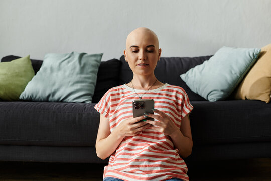 Bald woman with alopecia enjoys a peaceful moment at home while using her smartphone