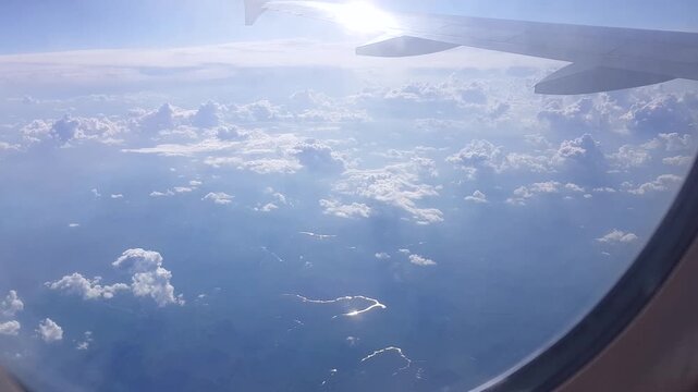 Window view airplane wing above clouds soft light and river glints below calm flight versatile shot for travel content openers weather news presentations and b roll