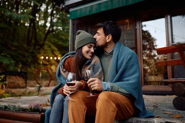 Romantic couple enjoying in glass of wine on patio in autumn.