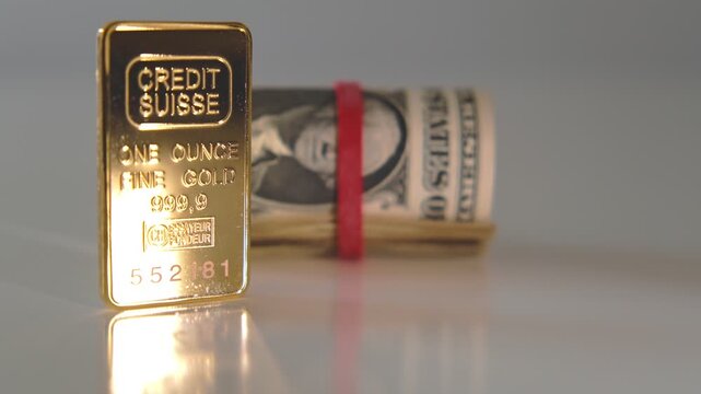 Pure one ounce gold bar from credit suisse bank with a roll of us dollar bills