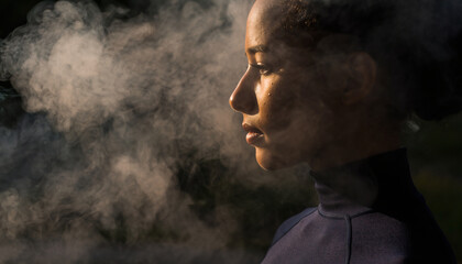 Woman exhales vapor in profile against dark background