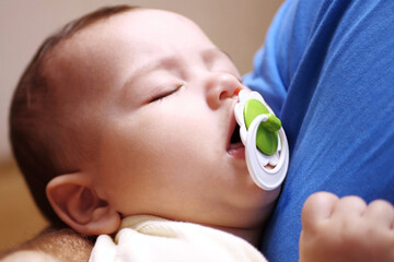 Cute newborn baby sleeping in father arms close up. A loving father carries her newborn baby at...
