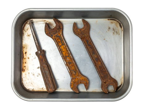 Rusty screwdriver and two open-end wrenches lying in a stained aluminum tray, vintage hand tools with heavy corrosion on isolated background