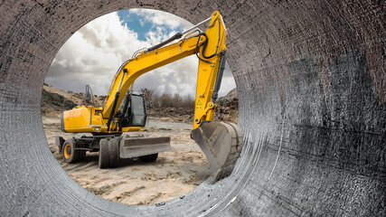 Heavy machinery is actively digging on a construction site, viewed through a large pipe that frames...