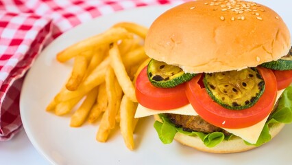 Delicious cheeseburger and crispy french fries on a white plate