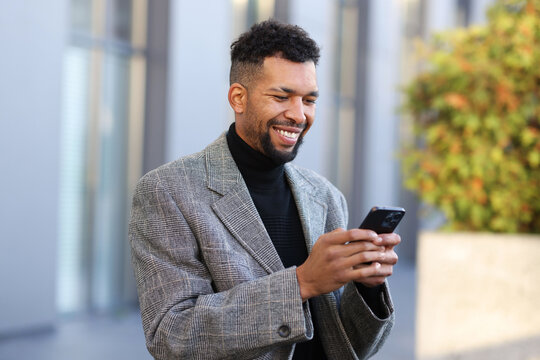 Smiling man in suit with smartphone on city street