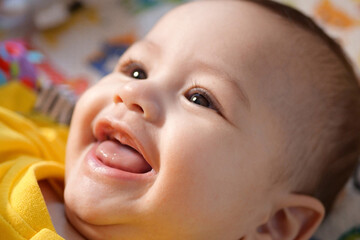 Happy newborn baby makes a funny face. Portrait of a crawling baby in his room close up