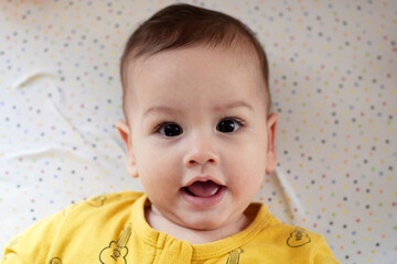 Happy newborn baby makes a funny face. Portrait of a crawling baby in his room close up
