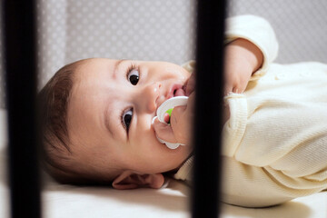 Baby sucking Pacifier looking on bed. portrait of cute newborn baby lying on bed with pacifier on...