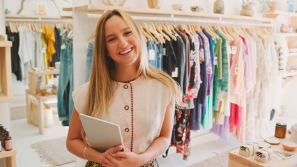 Portrait Of Young Female Sales Assistant With Digital Tablet In Clothing And Gift Store