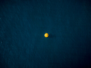 Aerial view of a vibrant yellow object contrasts against the deep blue sea, creating a striking visual focal point, Ksamil, Vlore County, Albania.