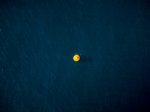 Aerial view of a vibrant yellow object contrasts against the deep blue sea, creating a striking visual focal point, Ksamil, Vlore County, Albania.