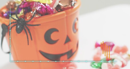 Fototapeta premium Sitting orange pumpkin bucket filling with candy on white table, spider, teal line and orange bars