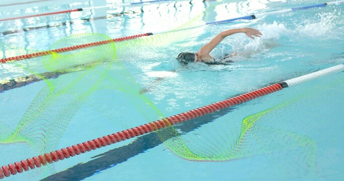 Swimming woman performing freestyle at lap pool, wearing cap, goggles, swimsuit, passing lane ropes