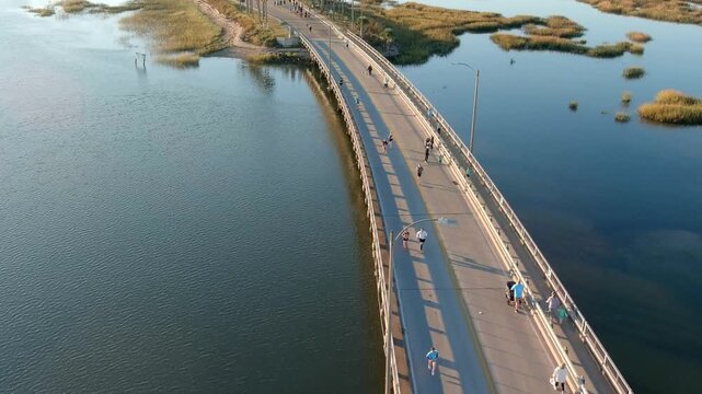 Aerial shot of people running a race across a bridge over water.