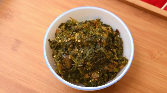Bengali dish Poi Saag (Malabar Spinach) with Baingan (eggplant), served in a white bowl on a wooden tray