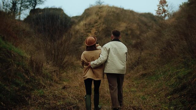 Romantic young couple hugging and carrying a pug dog while walking in a scenic autumn ravine - Powered by Adobe