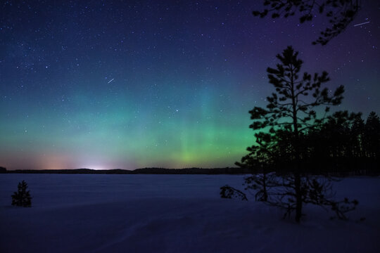 Green aurora borealis over a frozen and snowy lake in the forests of Pirkanmaa, Finland