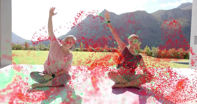 Instructor cue guiding two women stretching on mat on patio for fitness, particles overlaying frame