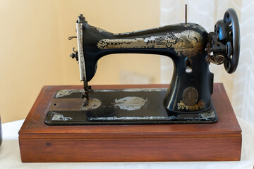 A vintage sewing machine with intricate designs sits on a polished wooden table in a well-lit space. The craftsmanship showcases details that reflect its historical significance.