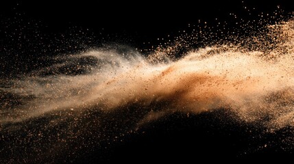 A swirling cloud of light brown dust particles explodes against a stark black background, creating a dynamic and textured abstract image with varying densities of the dust cloud