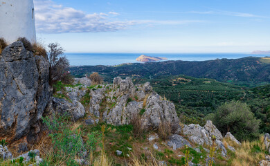 Panoramic landscape view of Crete coast with rocky foreground and distant island