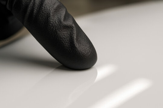 Touch of Precision: A gloved fingertip delicately explores a smooth, reflective surface, showcasing meticulous attention to detail and precision.