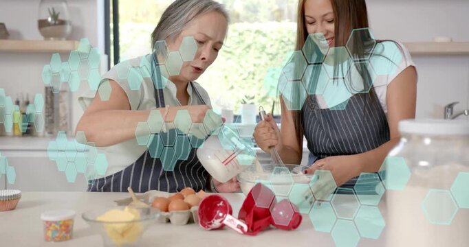 Adult pouring milk while teen stirring batter, hexagon overlaying counter guiding baking