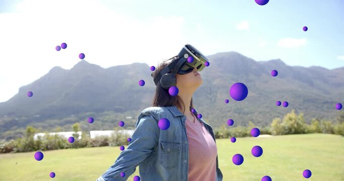 Teen wearing VR headset seeing purple orbs appearing, turning lowering arms in field testing AR