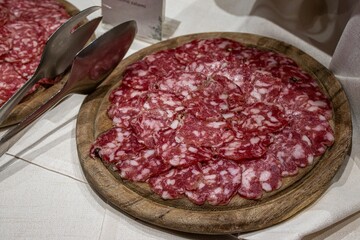 Sliced salami on wooden plate