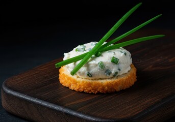 Vibrant green chives garnish a luxurious, creamy cheese appetizer bite on a dark wooden board, ready for a sophisticated party, organic, spring, gourmet