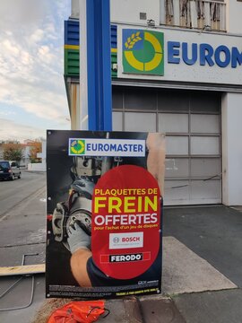 Royan, France - November 09, 2025: Euromaster automotive service advertisement featuring brake pads promotion with Bosch and Ferodo branding, located outside a garage in urban setting