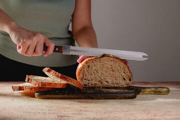 Woman Cutting Sourdough Loaf with Serrated Bread Knife