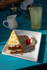 Yellow lemon cake on bright blue table with strawberry and cream