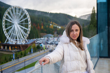 Woman in front of a Ferris wheel at a mountain resort.