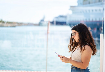 Smiling woman looking at her cell phone in the harbor