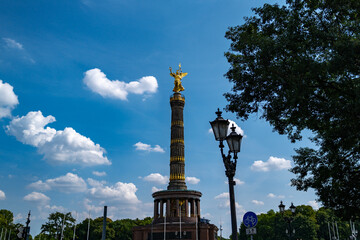Fototapeta premium Historic monument under bright sky. Golden statue Victory Column above Berlin. Tourists visit iconic Victory Column. Architectural details in Berlin.