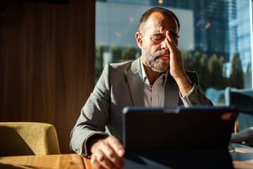 Mature businessman feeling stressed in modern office