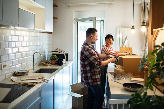 Happy adult couple packing boxes in bright home kitchen