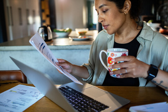 Adult woman focused, reviewing finances at home kitchen table