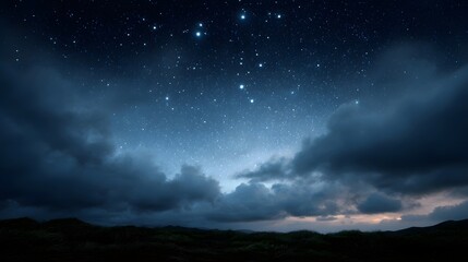 Fototapeta premium Dramatic night sky filled with stars and clouds over a dark landscape at dusk