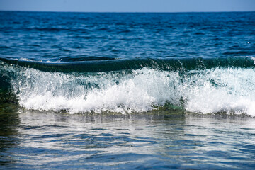 Fototapeta premium Day light on moving sea waves background. Ocean waves break and sparkle in sunlight. Blue sea waves shimmer in summer brightness. Waves splash. Sea wave an ocean texture.