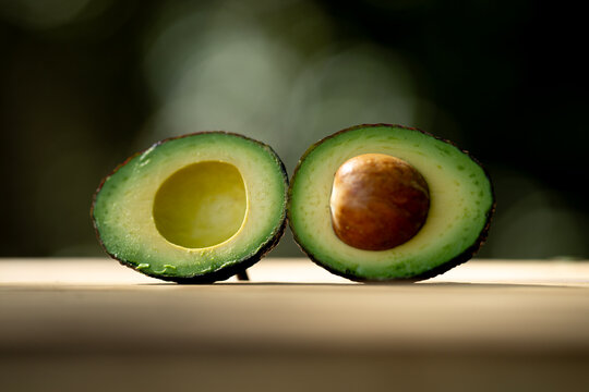 Fresh avocado half on green. Fresh ripe avocado. Avocado slice for healthy diet concept. Organic green fruit full of vitamins. Raw avocado.