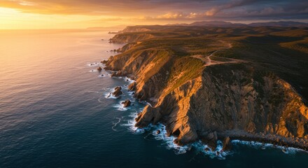 Aerial perspective captures dramatic, sunlit coastal cliffs meeting deep blue ocean waters at sunset
