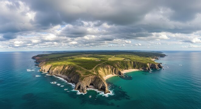 Expansive aerial view captures rugged coastal cliffs meeting vibrant turquoise ocean waters under a dramatic sky