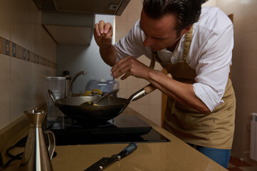 Caring Home Cook In Apron Focused On Pan On Stove In Cozy Kitchen